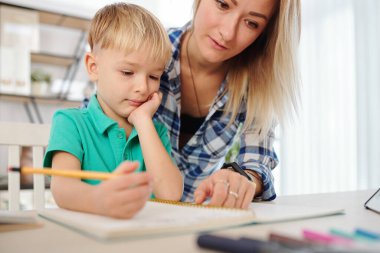 Anne, küçük oğluna ödev yaparken denklemi nasıl çözeceğini anlatıyor.