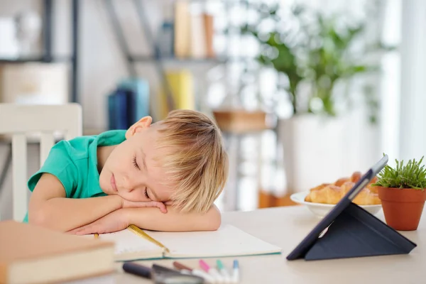 在平板电脑上看完枯燥乏味的教育视频后 疲惫的学童躺在桌子上睡觉 — 图库照片