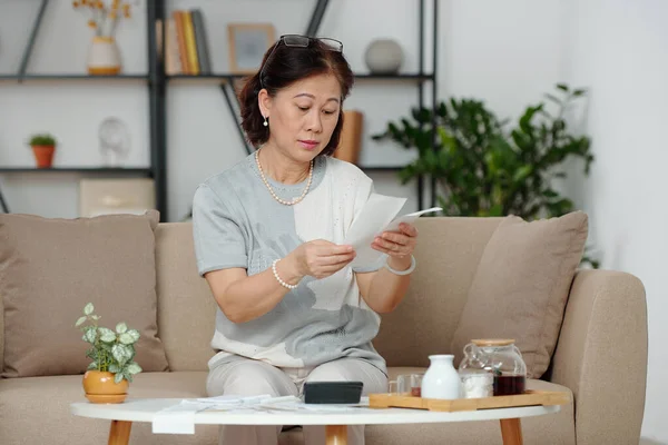 Überraschte Ältere Vietnamesin Sitzt Auf Couch Wohnzimmer Und Berechnet Hauskosten — Stockfoto