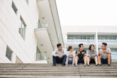 Bir grup arkadaş sabah birlikte koştuktan sonra basamaklarda oturup sağlıklı yaşam tarzlarını tartışıyorlar.