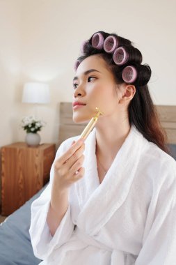 Çekici genç Asyalı kadın çene ve yanaklarına masaj yapıyor.