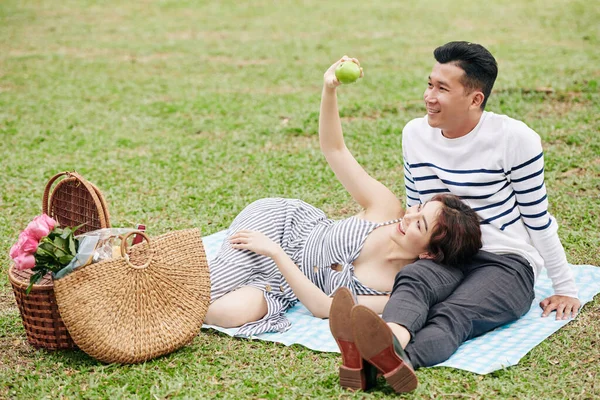公園でピクニックをしたり 果物を食べたり 話している美しい笑顔の若いアジアのカップル — ストック写真
