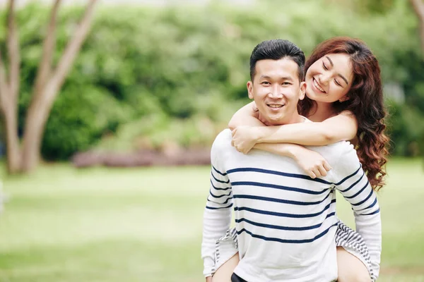 年轻的亚洲女人站在当地的公园里 从后面拥抱着她的男朋友 真是快乐极了 — 图库照片
