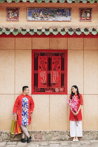 身着越南传统服装的男友和女友站在户外 手里拿着鲜花和购物袋 互相望着对方 — 图库照片