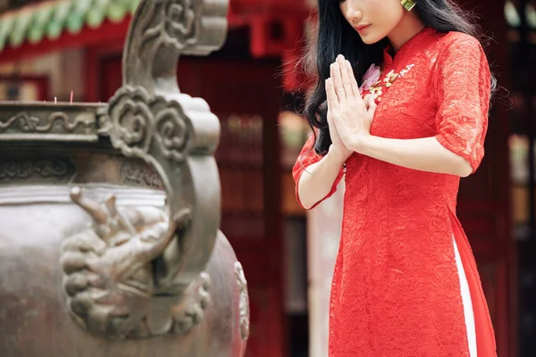 身穿传统红衣的年轻沉思女子在庙宇外祈祷的剪影 — 图库照片