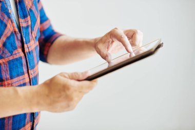 Ekose gömlekli olgun bir adamın tablet bilgisayarda yakınlaşan görüntüsü, seçici odak noktası