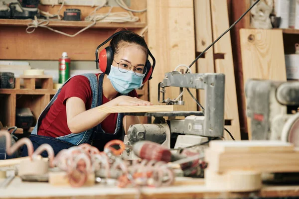 Tukang Kayu Muda Terkonsentrasi Dengan Earmuff Dan Masker Medis Memotong — Stok Foto