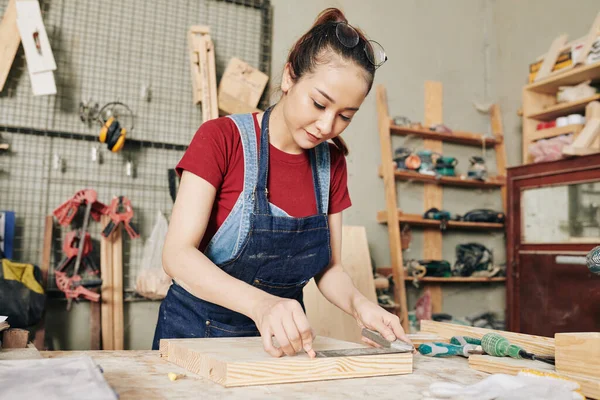 木製の板を測定し チョークの作品とマークを描く若い深刻な女性大工の肖像 — ストック写真