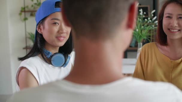 男性の友人の前でカフェに座って話をしていた二人の若いアジアの女性のバックビュー — ストック動画