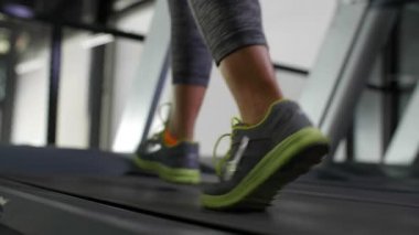Spor ayakkabılı kadın kaslı ayaklar spor salonunda koşu bandında koşar.