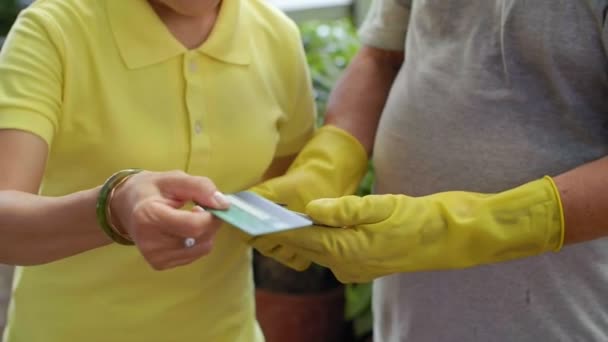 在黄色橡胶手套上贴有专用设备的平板机的卖家关门 买主用卡片支付购买费用 — 图库视频影像