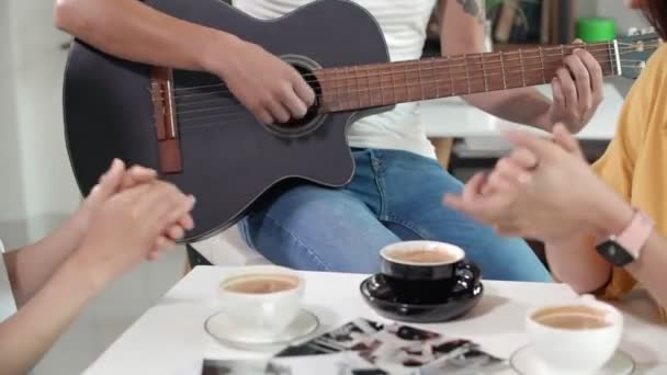 近くに座っている男に拍手2人の女性の手を閉じるとギターを演奏 — ストック動画