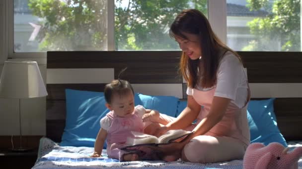 Średnie Ujęcie Azjatki Jej Dziecka Siedzących Łóżku Przeglądających Książkę — Wideo stockowe