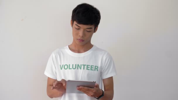 用平板电脑把身穿志愿制服的亚洲年轻人关起来 然后看着相机笑了 — 图库视频影像