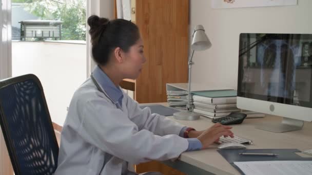 Средний Снимок Женщины Азиатского Врача Сидящей Компьютером Офисе Печатающей Клавиатуре — стоковое видео