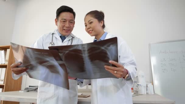 亚洲男医生和他的女同事手拿着X光片站在一起 透过他们的视角很低 — 图库视频影像