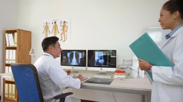 Egy Férfi Ázsiai Orvos Zárlata Aki Asztalnál Röntgenfelvételekkel Nézi Képernyőket — Stock videók
