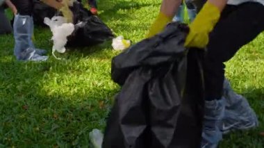 Bir grup genç Asyalı gönüllü çimlerden çöp topluyor.