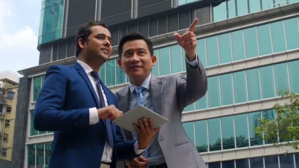 Medium Shot Two Asian Businessmen Standing Outdoors Tablet Discussing Surroundings — Stock Video