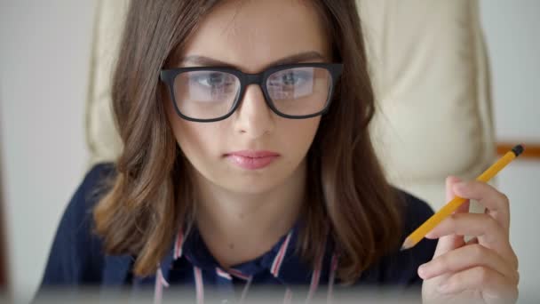 何かを見て指で鉛筆を捻り笑顔で座っている若い女性の中に — ストック動画