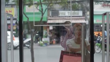 Çekici stil sahibi Asyalı kadınlar cam kapılar açıyor, pahalı moda mağazalarına giriyor ve heyecanla gülümsüyorlar. 