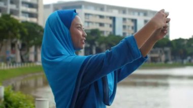 Genç çekici Asyalı kadın oturma odasında kanepede oturmuş kitap okuyor ve kocasını beklerken dikkatlice pencereden dışarı bakıyor. 