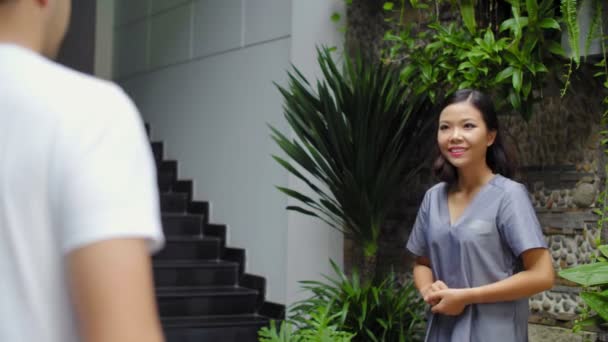 水疗中心附近身着制服的亚洲女性向男性顾客致意的中镜头 — 图库视频影像