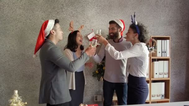 オフィスで企業のクリスマスパーティーを持っている若いオフィスマネージャーの多民族グループ シャンパンを飲みます 陽気にチャットや笑顔 — ストック動画