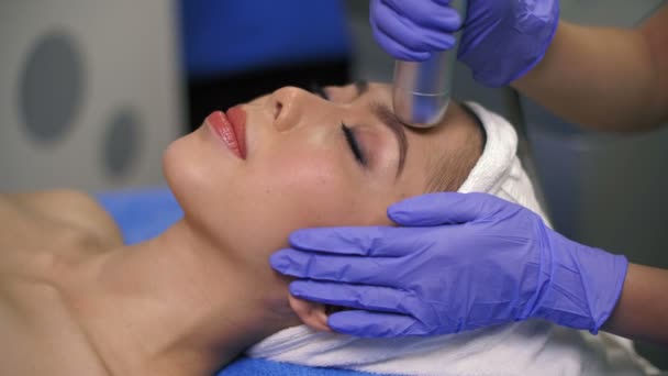 美容師と顔をマッサージしながら治療台の上に寝そべって目を閉じたアジアの女性のクローズアップ — ストック動画