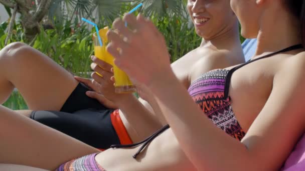 若いですアジアの男性と女性のビーチウェアで横たわっスイミングプールと飲み物カクテル — ストック動画