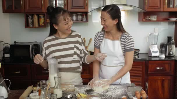 迷人的亚洲女人一边揉搓饼干面团 一边给漂亮的女儿加面粉 抹去双手 开心地笑着 — 图库视频影像