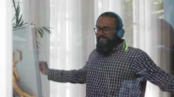 Medium Shot Young Indian Man Beard Sitting Headphones Computer Stretching — Stock Video