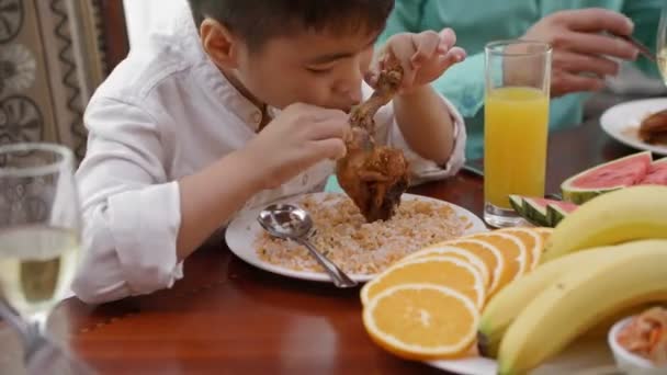 Zamknij Talerz Ryżem Smażoną Nogą Kurczaka Małym Azjatyckim Chłopcem Gryzącym — Wideo stockowe