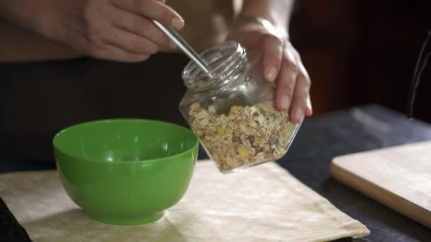 Menutup Tangan Manusia Menuangkan Muesli Dalam Piring Hijau Dan Mengisinya — Stok Video