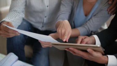 Tanımlanamayan bir çiftin kanepeye oturup dijital emlak danışmanlığı tabletindeki yeni evlerinin resimlerine yakından bakması.
