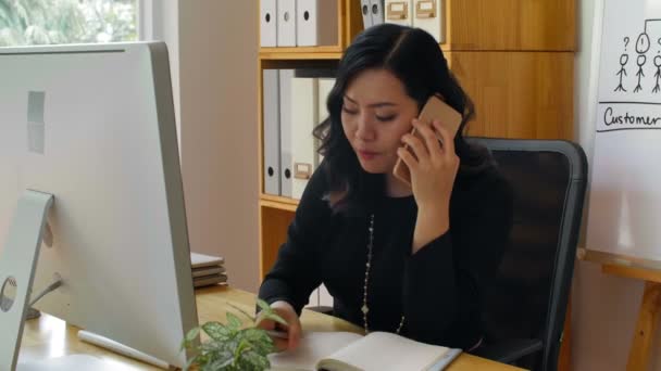 Fiatal Csinos Ázsiai Irodai Asztalnál Dolgozik Számítógépen Beszél Okostelefonon Ügyféllel — Stock videók