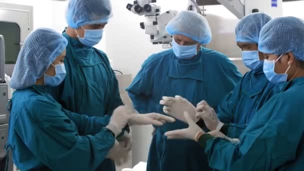 Grupo Cirurgiões Profissionais Assistentes Vestindo Uniformes Máscaras Sala Cirurgia Colocando — Vídeo de Stock