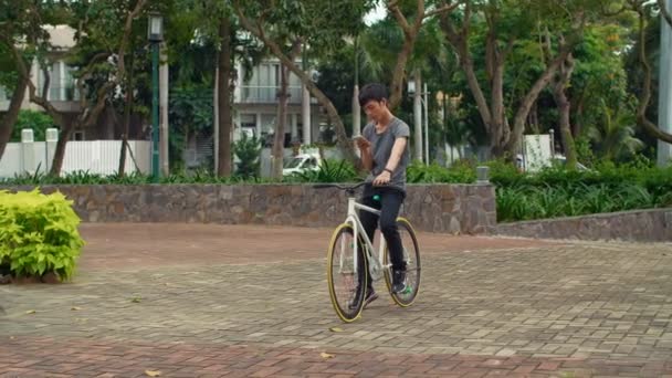 Amplio Tiro Joven Asiático Sentado Bicicleta Usando Teléfono Luego Ponerlo — Vídeo de stock