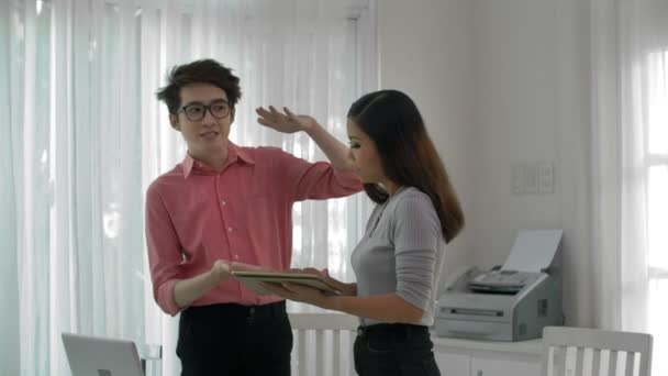 亚洲年轻男性办公室职员的中镜头 向手持平板电脑的女同事解释未来策略的几点 — 图库视频影像
