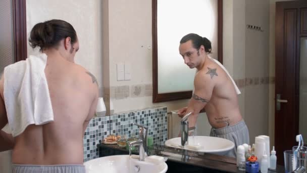 中くらいのショットの白人男性とともに裸の胴がバスルームに沈みます 鏡を見て彼の歯をブラッシング — ストック動画