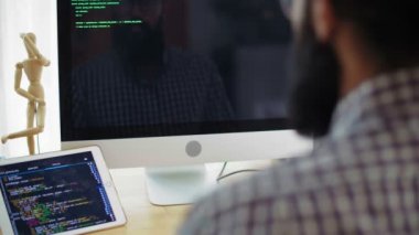 Bilgisayar ekranının önünde oturan, program kodunu yazan ve sonra da telefona cevap veren nadir bir adam görüntüsü.