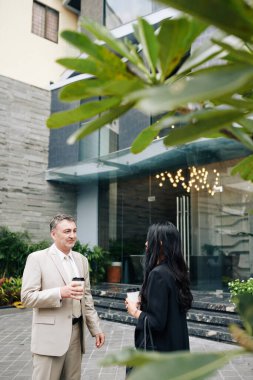 Olgun girişimci, dışarıda genç bir meslektaşla konuşurken kahve içer.