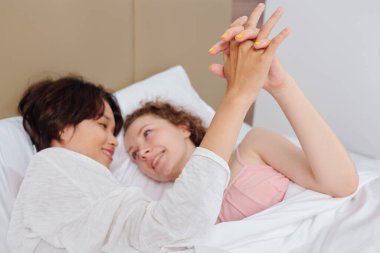 Gülümseyen güzel sevgililer yatakta sarılıp birbirlerine bakıyorlar.