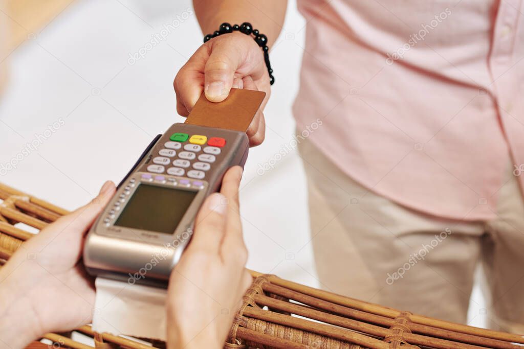Close-up image of male spa hotel guest paying with credit card for room service