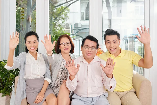 Glimlachende Familie Van Vier Zitten Bank Thuis Zwaaien Met Handen — Stockfoto