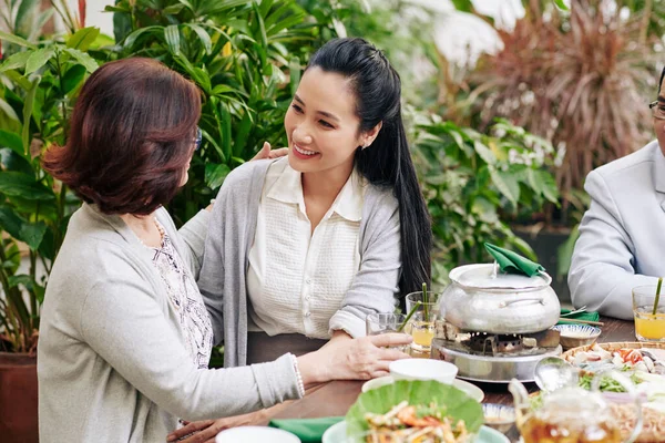 母亲抱着她的成年女儿坐在餐桌前庆祝家人团聚 — 图库照片