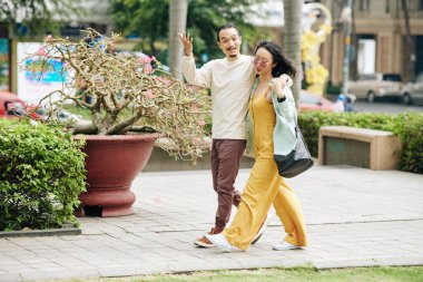 Komik, genç, şık Asyalı kucaklaşmacı çift sokakta yürürken duygusal bir konuşma yapıyor.