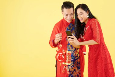 Çin Yeni Yılı için süslemeleri olan mutlu genç bir çift. Akıllı telefondan en iyi dileklerimle yazılar okunuyor.