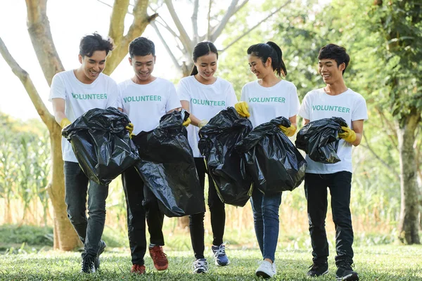 Bir grup Asyalı genç birlikte gönüllü olarak vakit geçirip parkta çöp toplamaktan zevk alıyor.