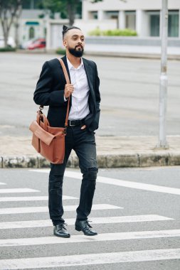 Deri çantalı yakışıklı sakallı adam karşıdan karşıya geçiyor.